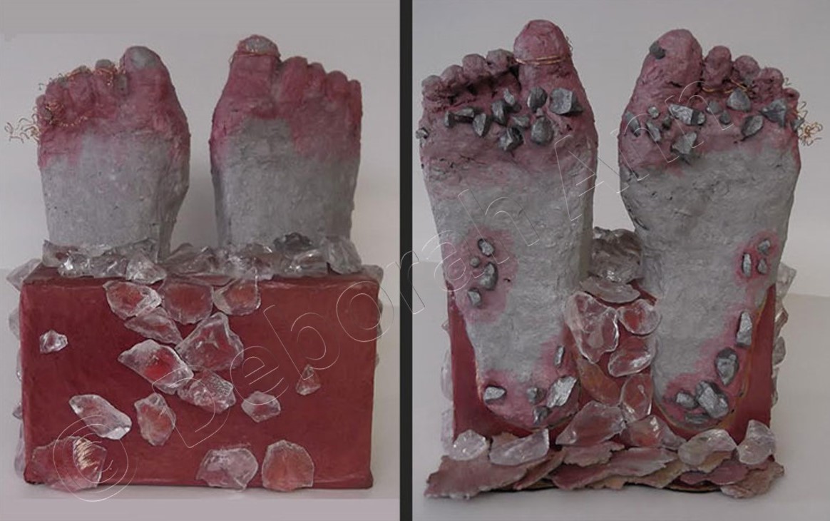 clay feet in red box with ice cubes and debris, feet are red and grazed